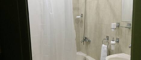 A bathroom with a bathtub, a shower, a sink, and a mirror.