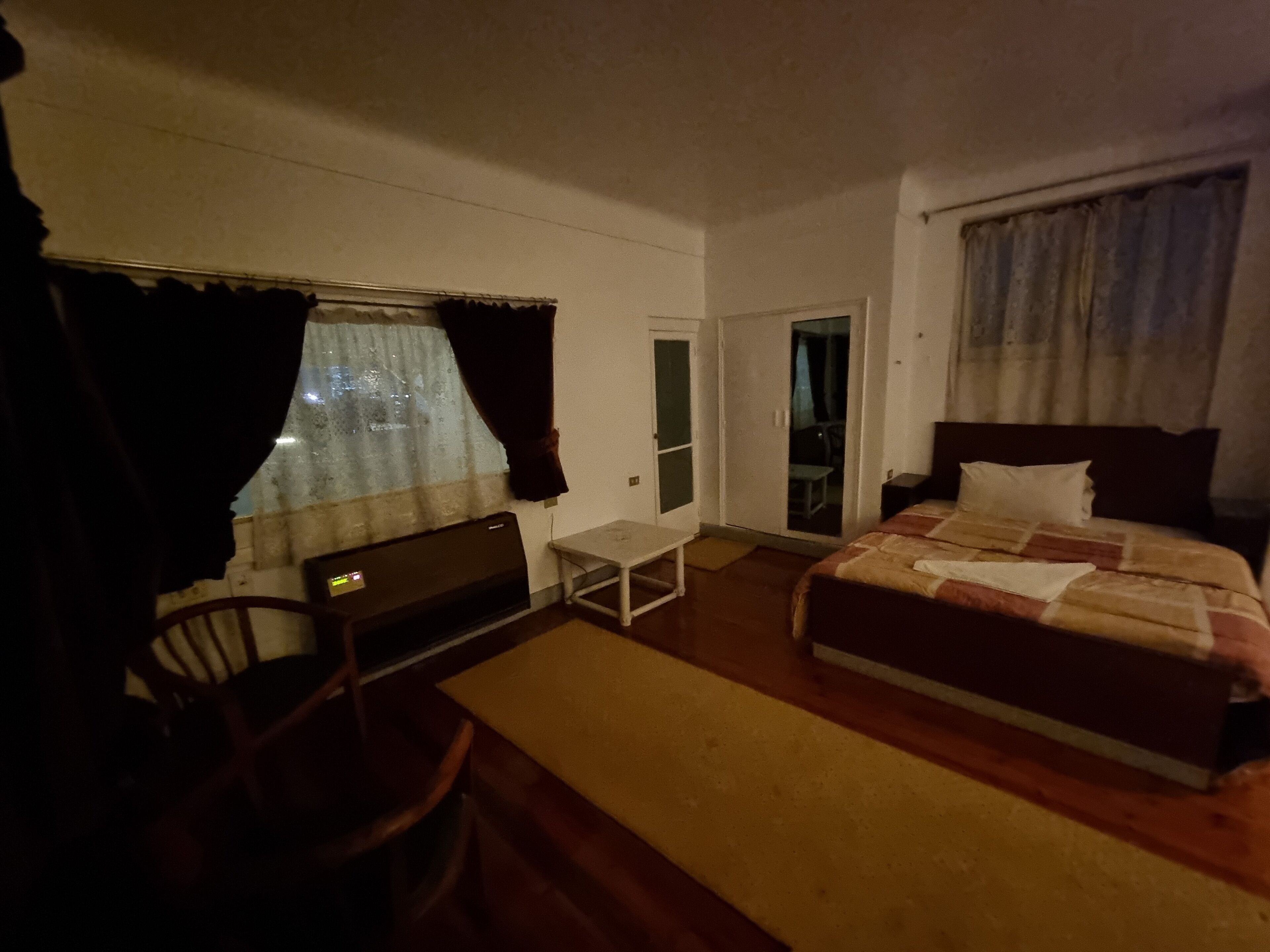 A hotel room with a bed, a desk, a chair, and a small table.