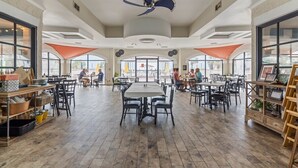 Een ruim restaurant met hoge plafonds, grote ramen en een centrale eetruimte met meerdere tafels en stoelen.
