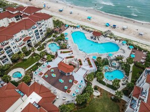 An aerial view of a resort with multiple swimming pools, a beach, and a large building with balconies. - Suite Escape, Villa Capriani's only Luxury Studio - 3 pools & 2 hot tubs!  (North Topsail Beach)