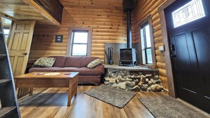 A log cabin interior with a wooden ceiling, a stone fireplace, a sofa, and a dining table. - Reboot, Recover, Recreate…Centrally located 20 acre Mill Creek getaway cabin! (Anaconda)