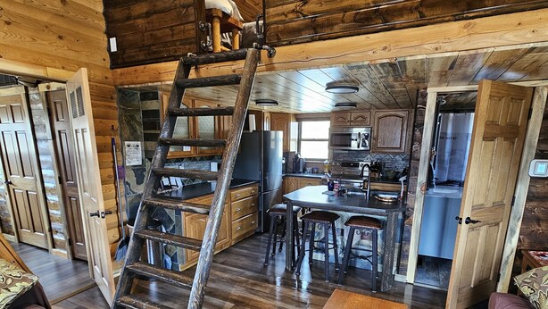 A rustic cabin interior with a wooden staircase, a dining area, and a kitchen. - Reboot, Recover, Recreate…Centrally located 20 acre Mill Creek getaway cabin! (Anaconda)