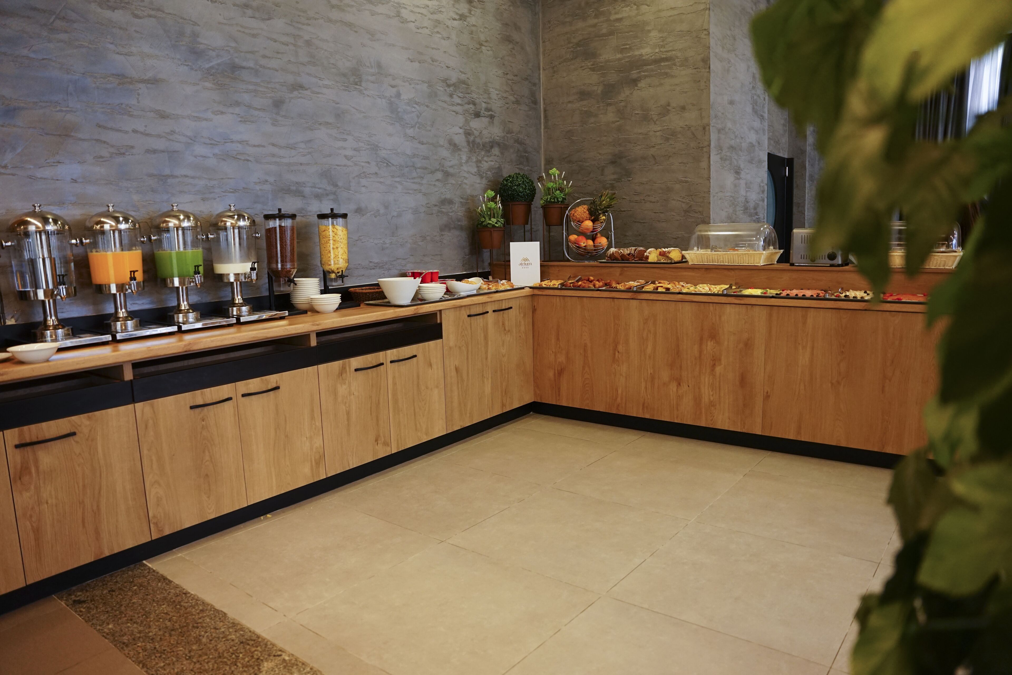 A modern kitchen with wooden cabinets, a black countertop, and a variety of food dispensers.
