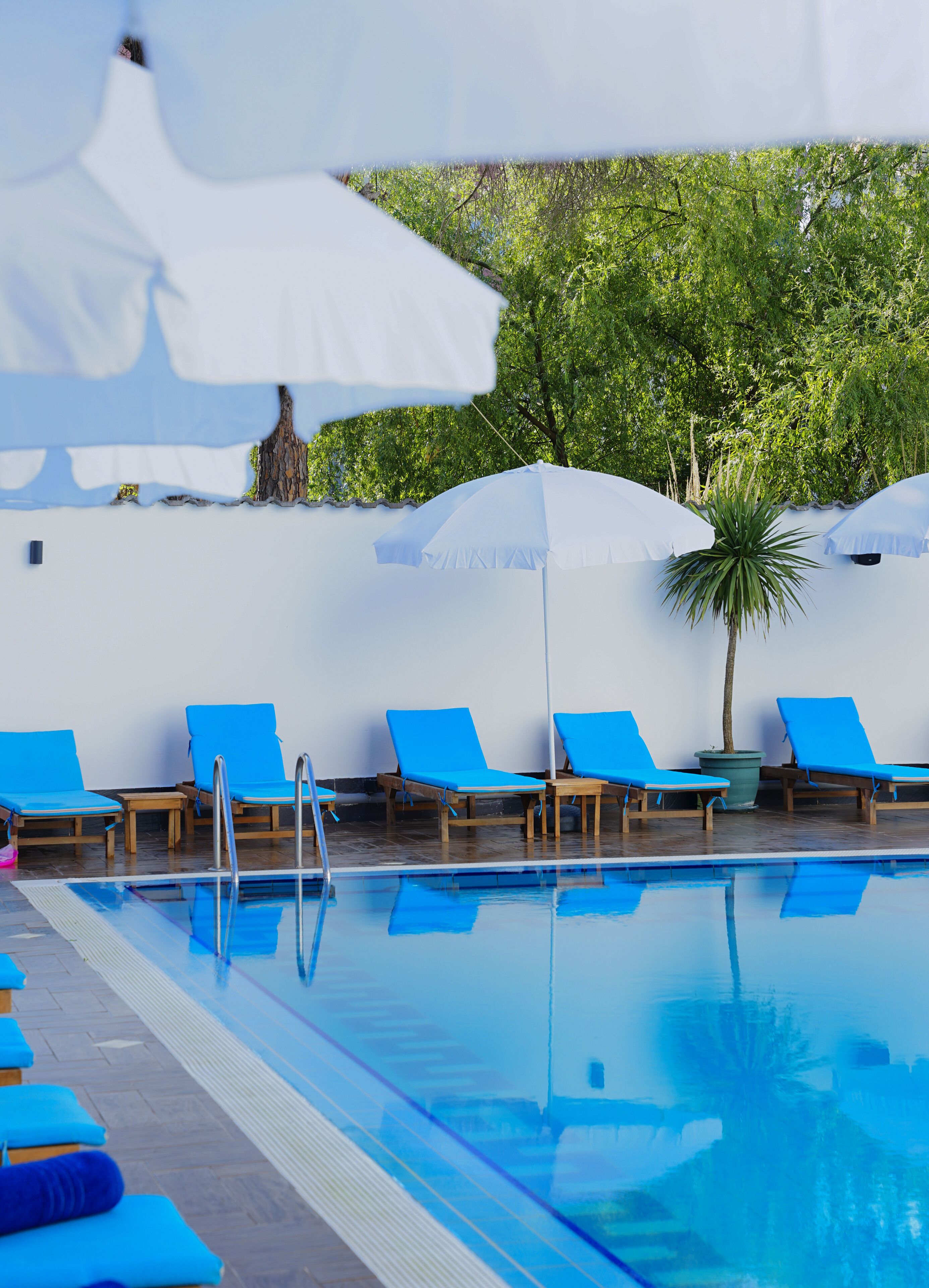 A pool area with blue lounge chairs and white umbrellas.