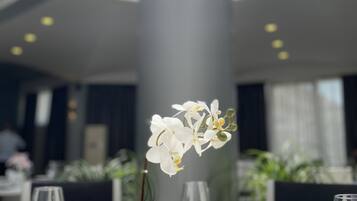 A dining table with a potted orchid, a wine glass, and a plate.