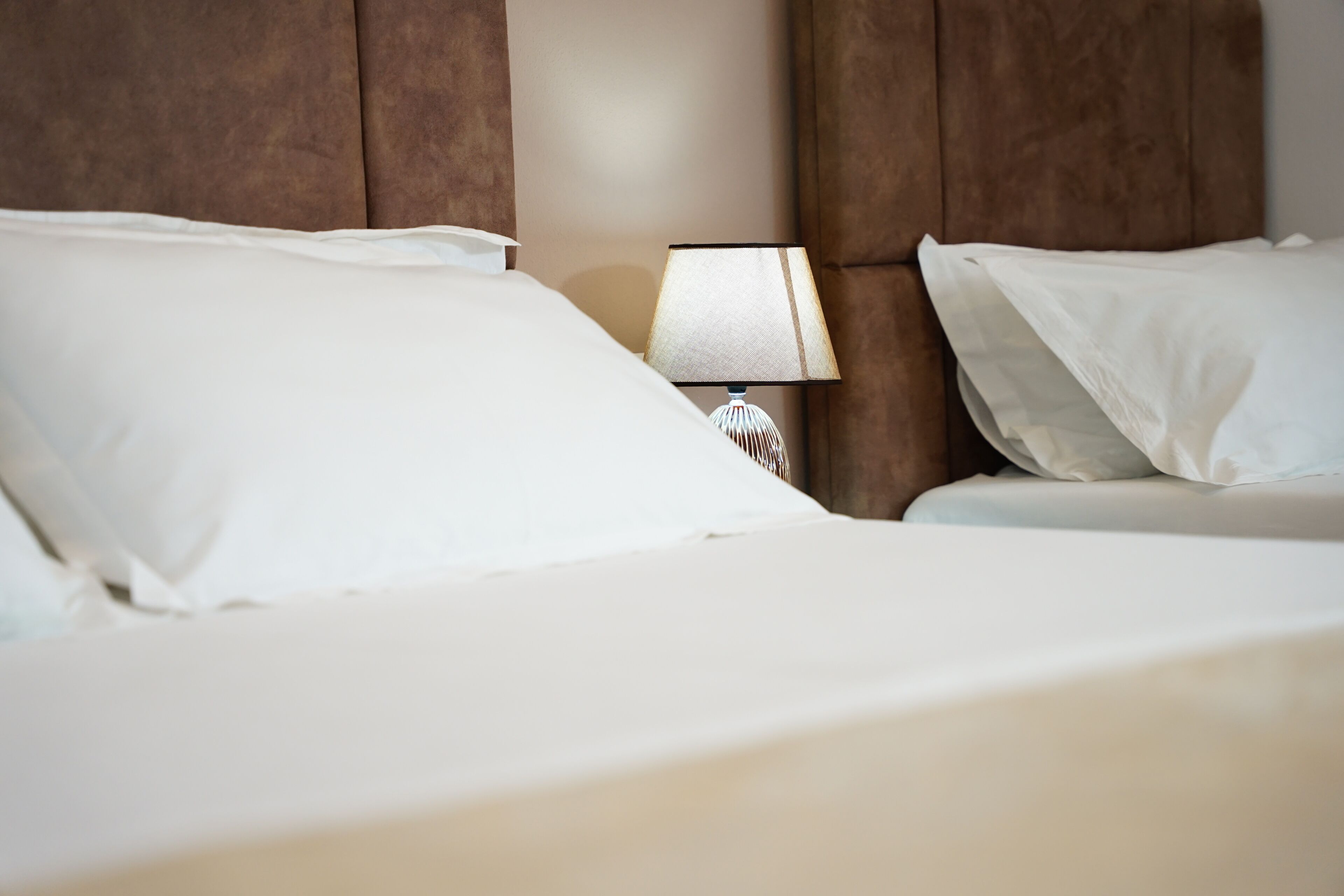 A hotel room with a bed, pillows, and a bedside lamp.
