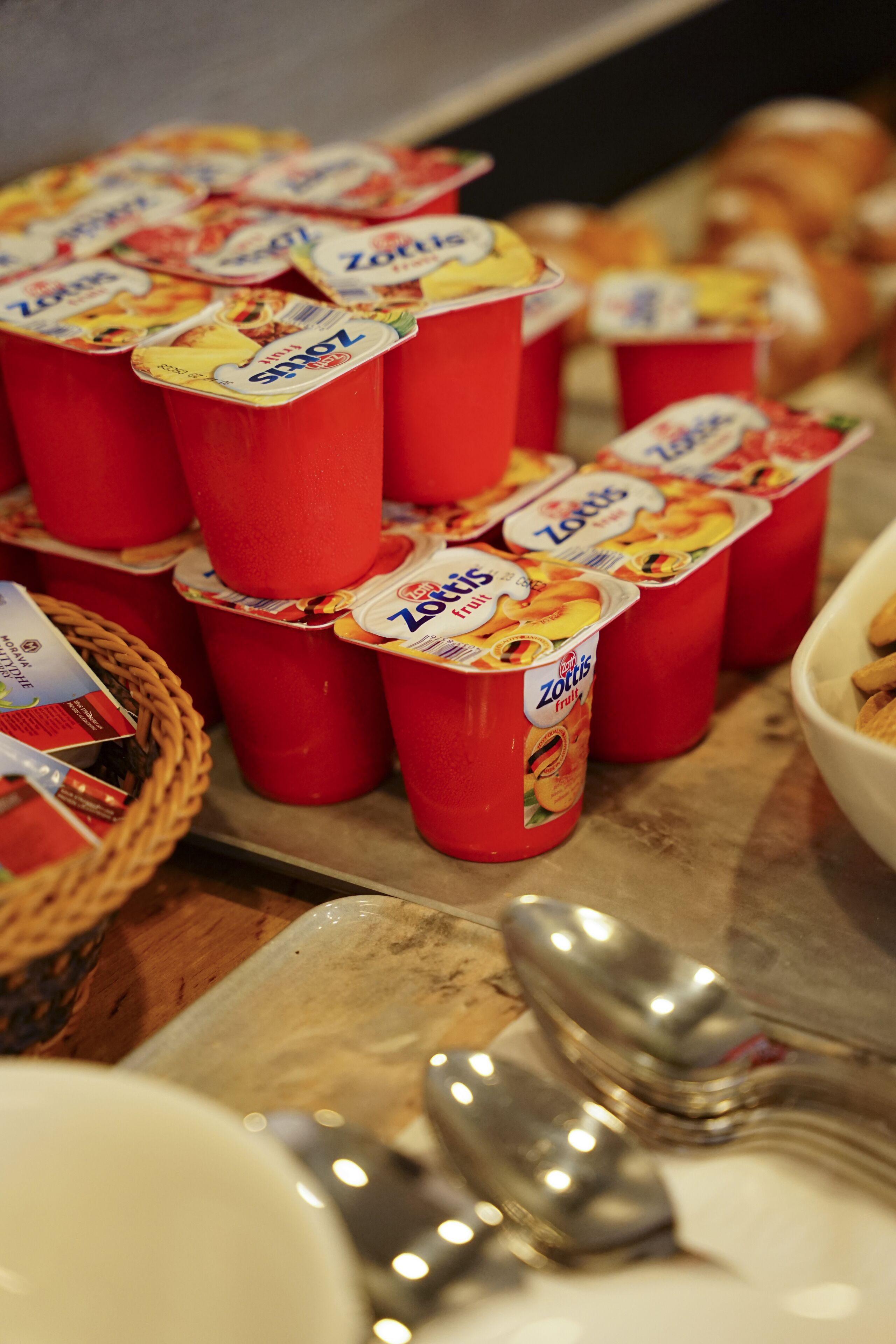 Une table avec des pots de yaourt rouges et un panier de pain.