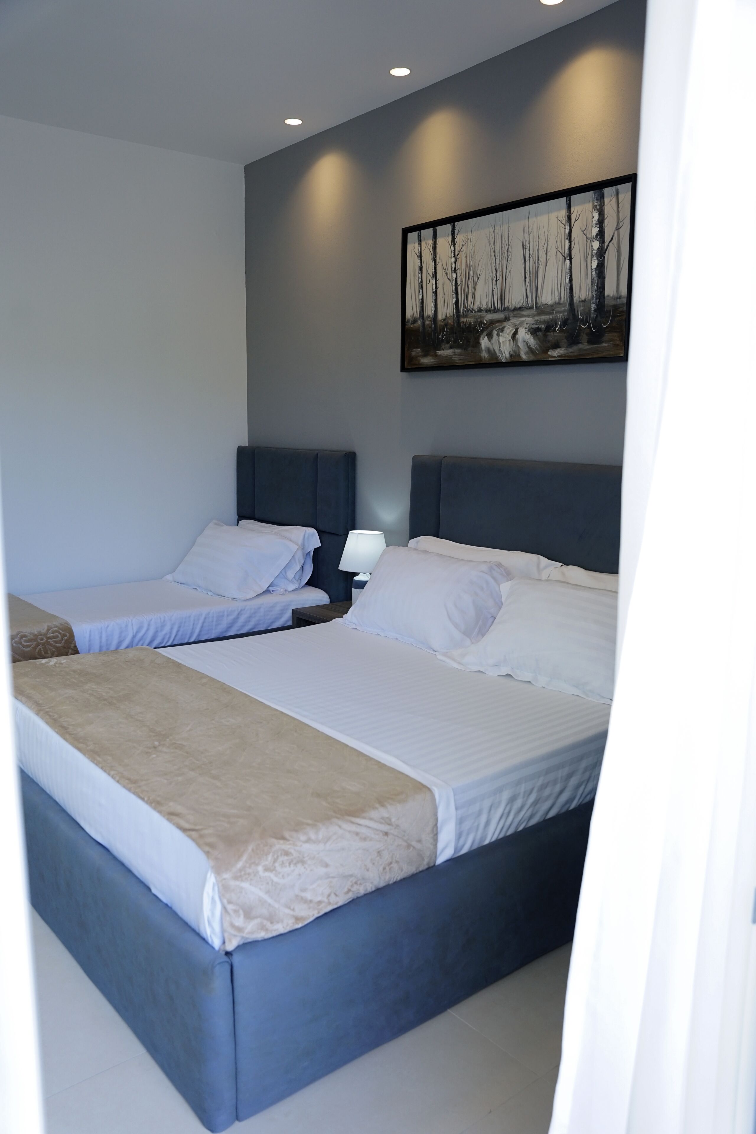 Ein Hotelzimmer mit zwei Betten, einem Nachttisch, einer Lampe und einem Bild an der Wand.