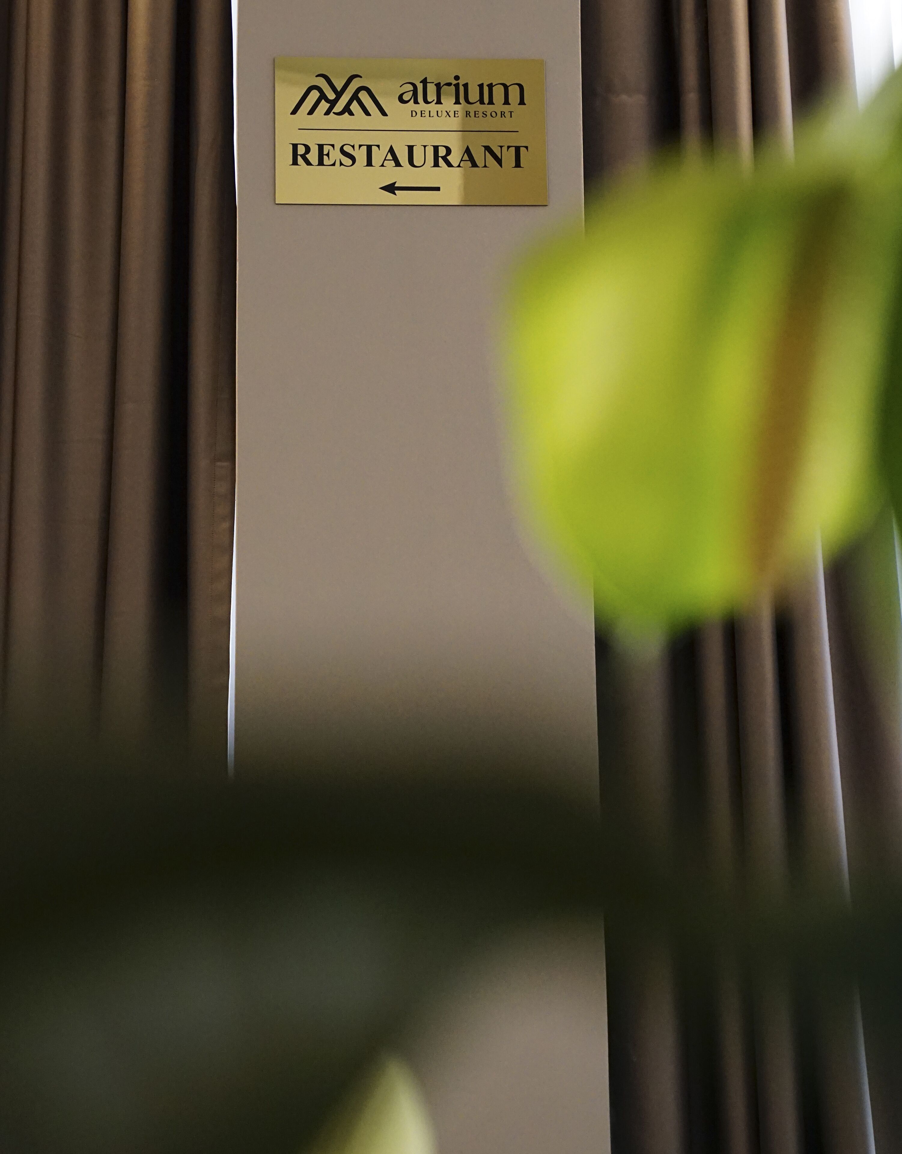 A sign for Atrium Deluxe Resort Restaurant with an arrow pointing left.