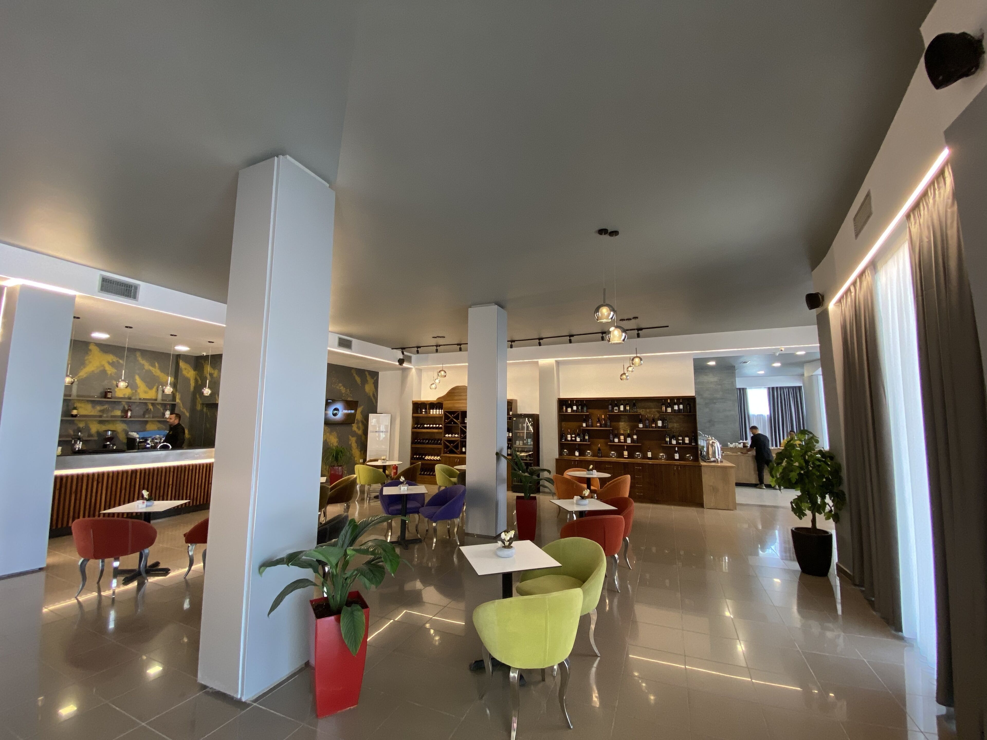 Eine moderne Hotelhalle mit Barbereich, Sitzgelegenheiten und einer Weinauslage.