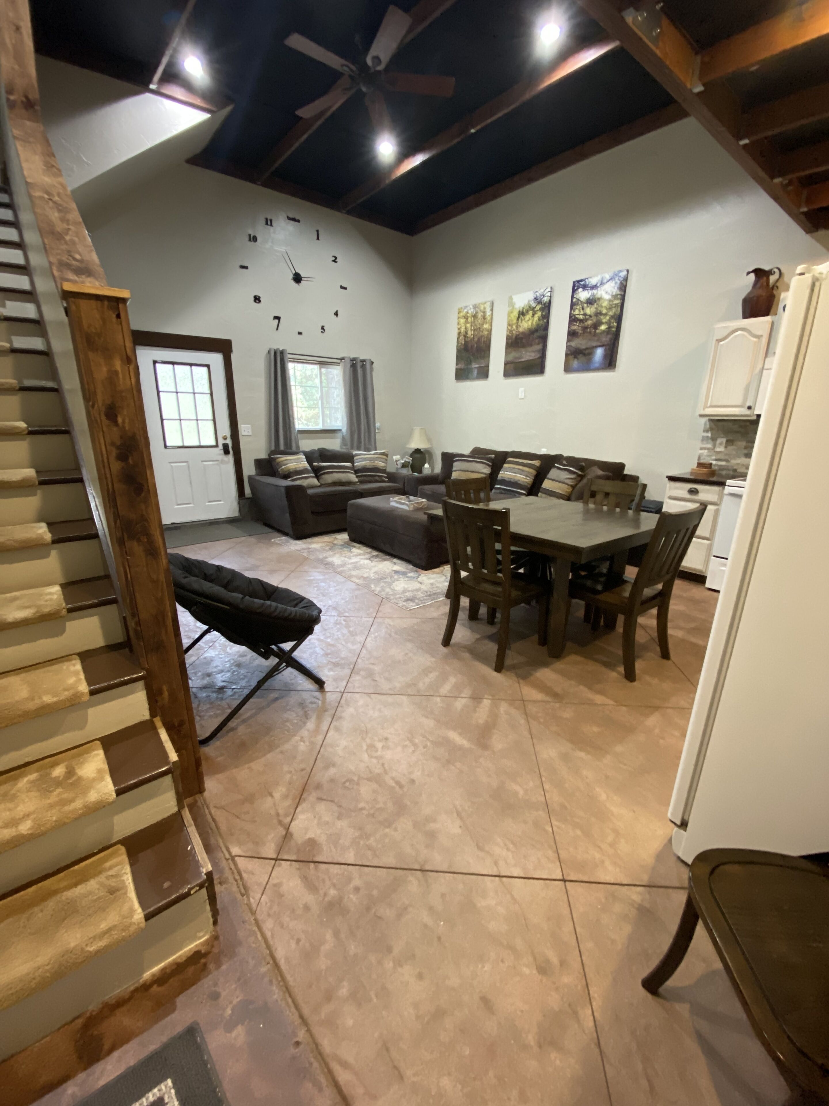 Amplia sala de estar con una mesa de comedor y sillas, un sofá y una escalera.