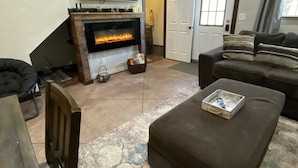 A living room with a fireplace, a television, a sofa, and a coffee table. - Cozy home with HOT TUB, River View & Fire Pit! (Garden Valley)