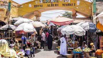 Un marché animé, avec une arche imposante portant l’inscription « ROYAL ALBERT MARKET ».