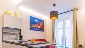 A modern kitchen with a bar area, a dining table, and colorful bar stools. - Golden Terrace at Historical Center (Naples)