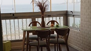 En matplats med ett bord och fyra stolar, en prydnadsväxt och utsikt över havet.