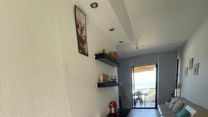 A modern living room with a sofa, a coffee table, and a kitchen area with a kettle and a kettle on the counter. - Keserouane Cozy Apartment With a View (Dbayeh)