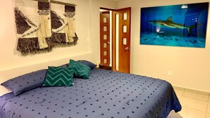 Une chambre à coucher avec un lit, une décoration murale et un tableau représentant un requin.