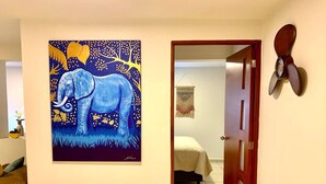 Un couloir orné d’un tableau représentant un éléphant, un lit et une porte dotée d’une poignée en bois.
