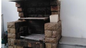 Una parrilla de piedra para exteriores con chimenea blanca, frente a una pared lisa.