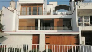 Edificio de dos pisos con un balcón en el nivel superior, puerta de garaje y una valla blanca al frente.