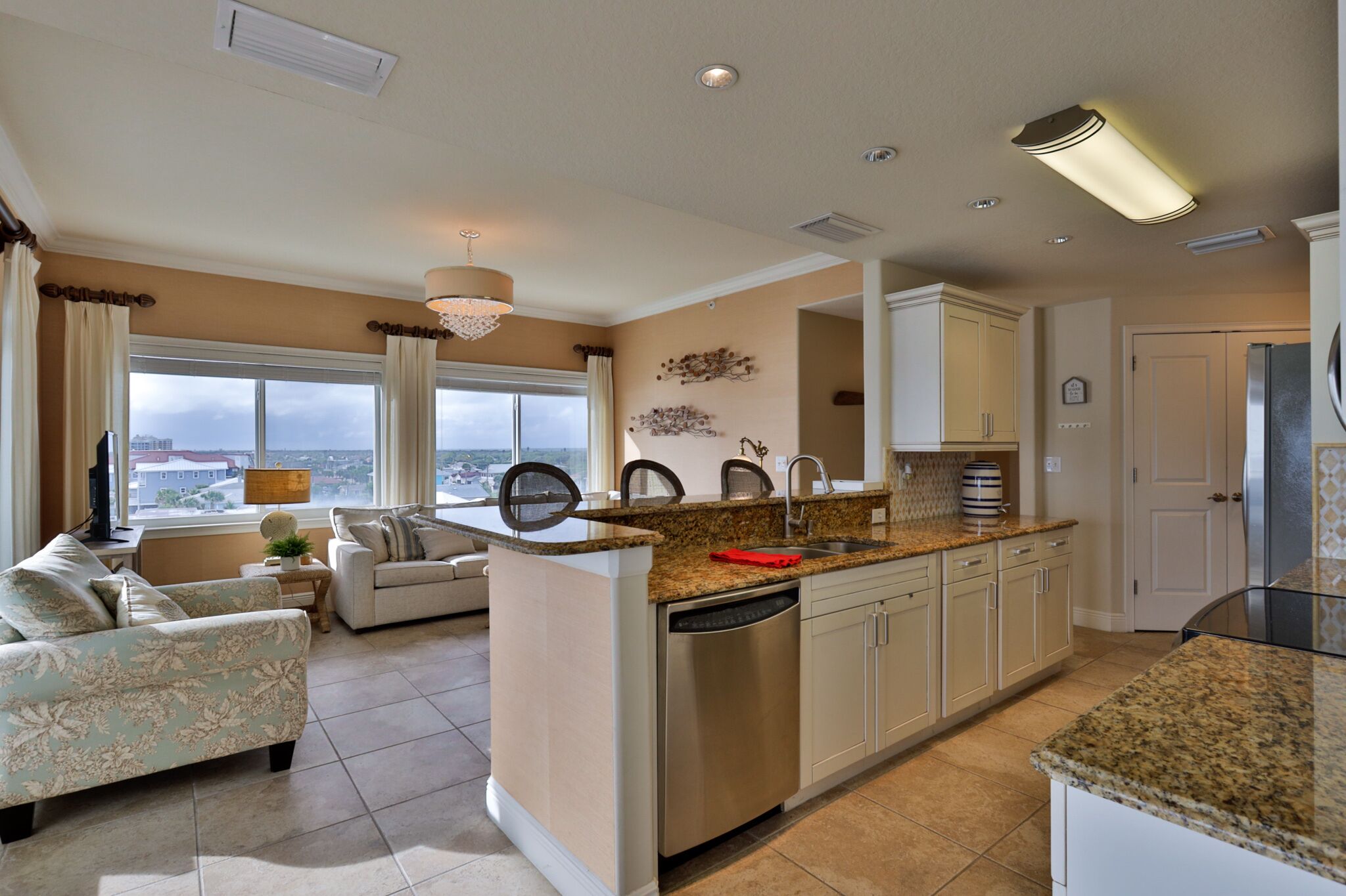 A modern kitchen with a central island, built-in appliances, and a dining area with a sofa and a view of the city.