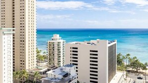 Een hoog hotel met uitzicht op de oceaan en palmbomen.