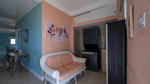 Ein Wohnzimmer mit einer Couch, einem kleinen Tisch, einem Kühlschrank und einem Fernseher.