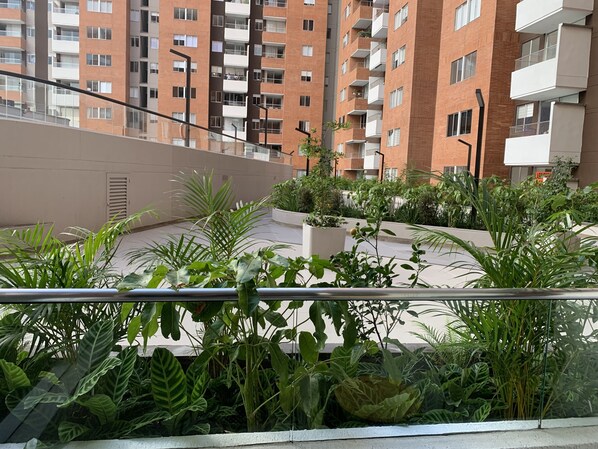 Ein Balkon mit üppigem Grün und Blick auf ein mehrgeschossiges Wohngebäude.