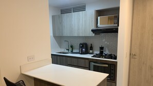 A compact kitchen with a white countertop, a built-in microwave, a coffee maker, and a wine bottle. - 3BR magical aparment in the heart of Medellin - Poblado  (Medellín)