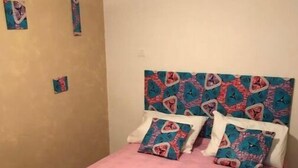 A bedroom with a bed covered in pink bedding, a patterned headboard, and two pillows. - un Appart Haut Alpin Chez les Chtis (Gap)