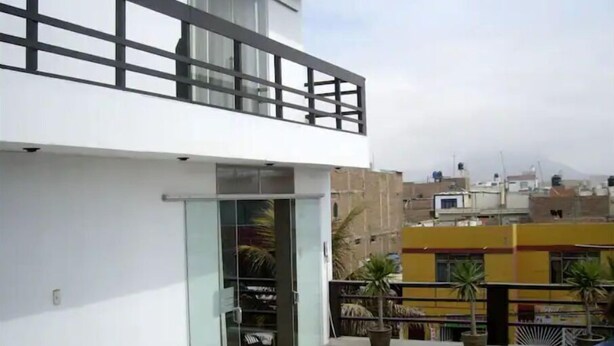 Un edificio moderno con balcón, puertas de vidrio y plantas en macetas.