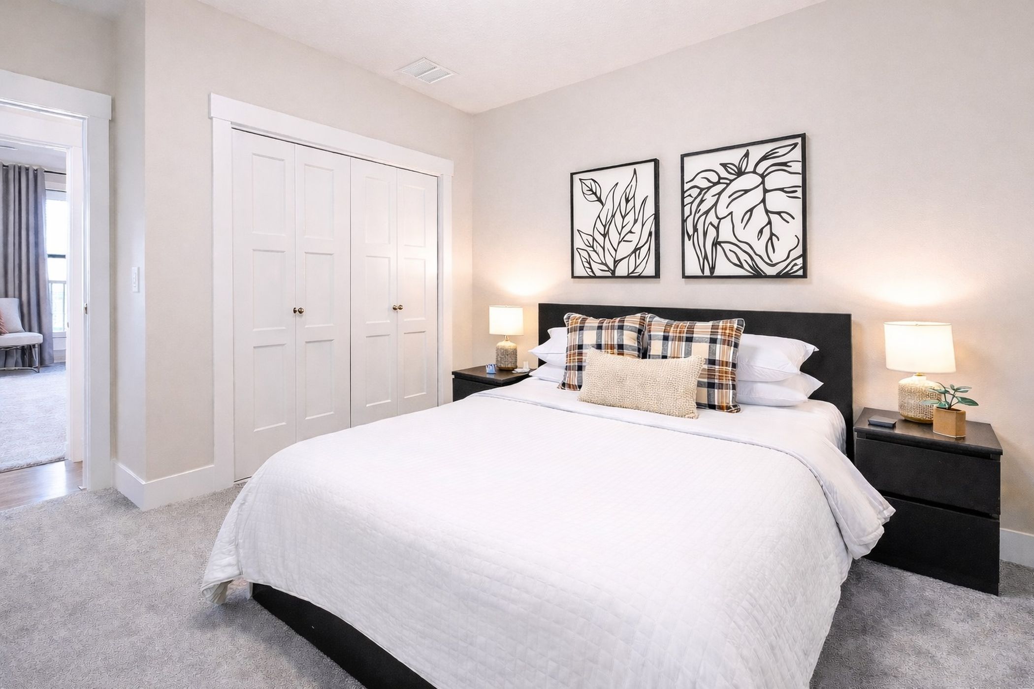 A bedroom with a large bed, two nightstands, a wardrobe, and two wall art pieces.