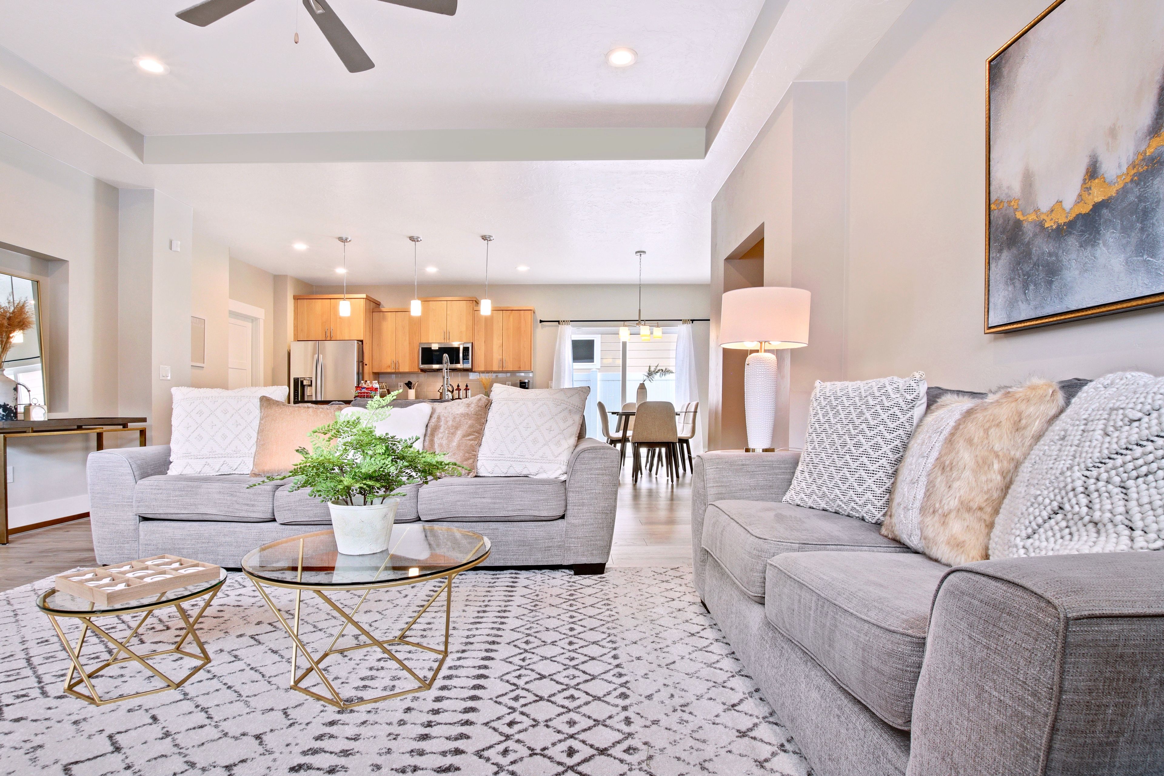 A modern living room with a grey sofa, a glass coffee table, and a patterned rug.