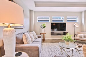 Un salon moderne avec un canapé, une table basse et un téléviseur.