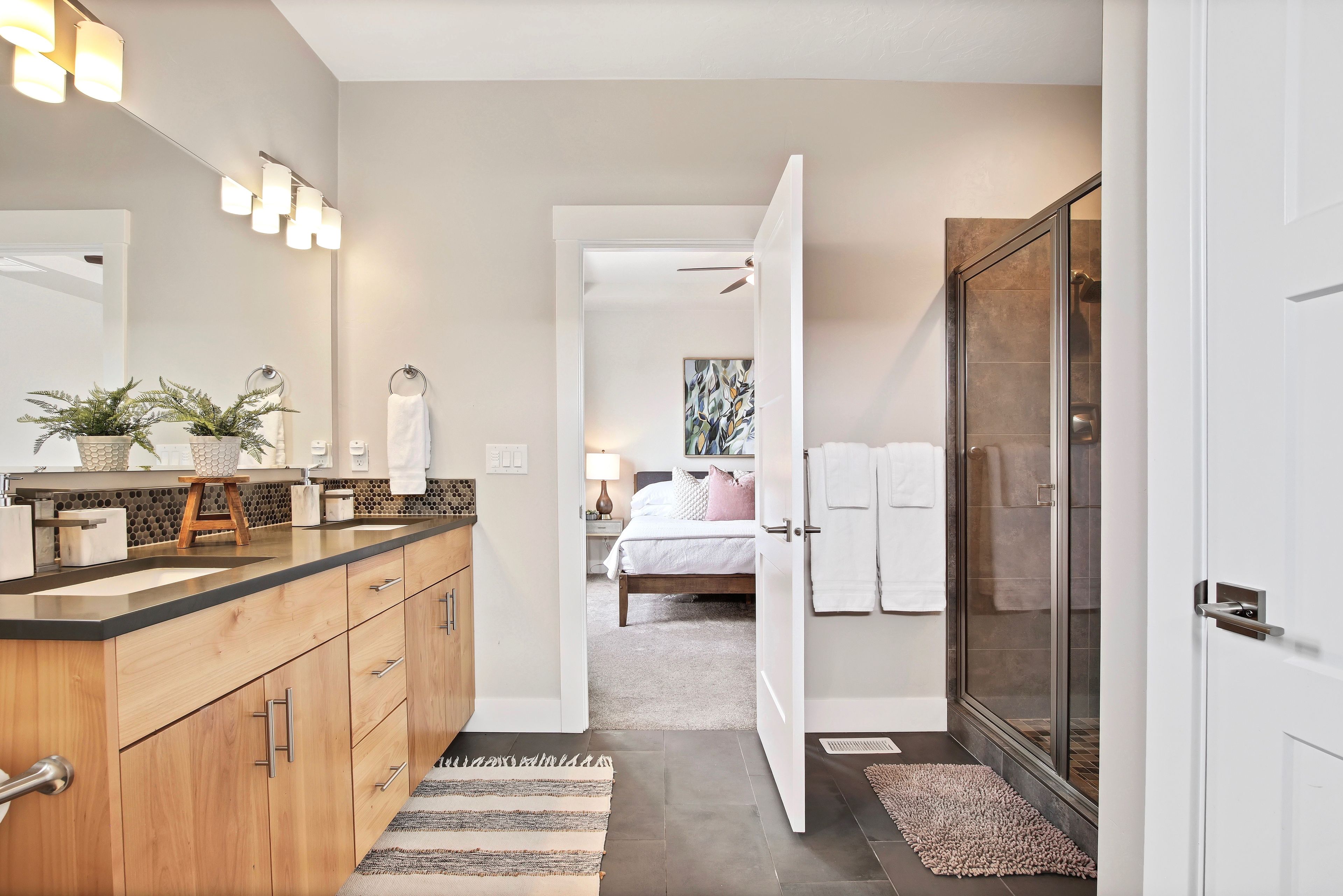 A modern bathroom with a vanity, mirror, and towel rack.