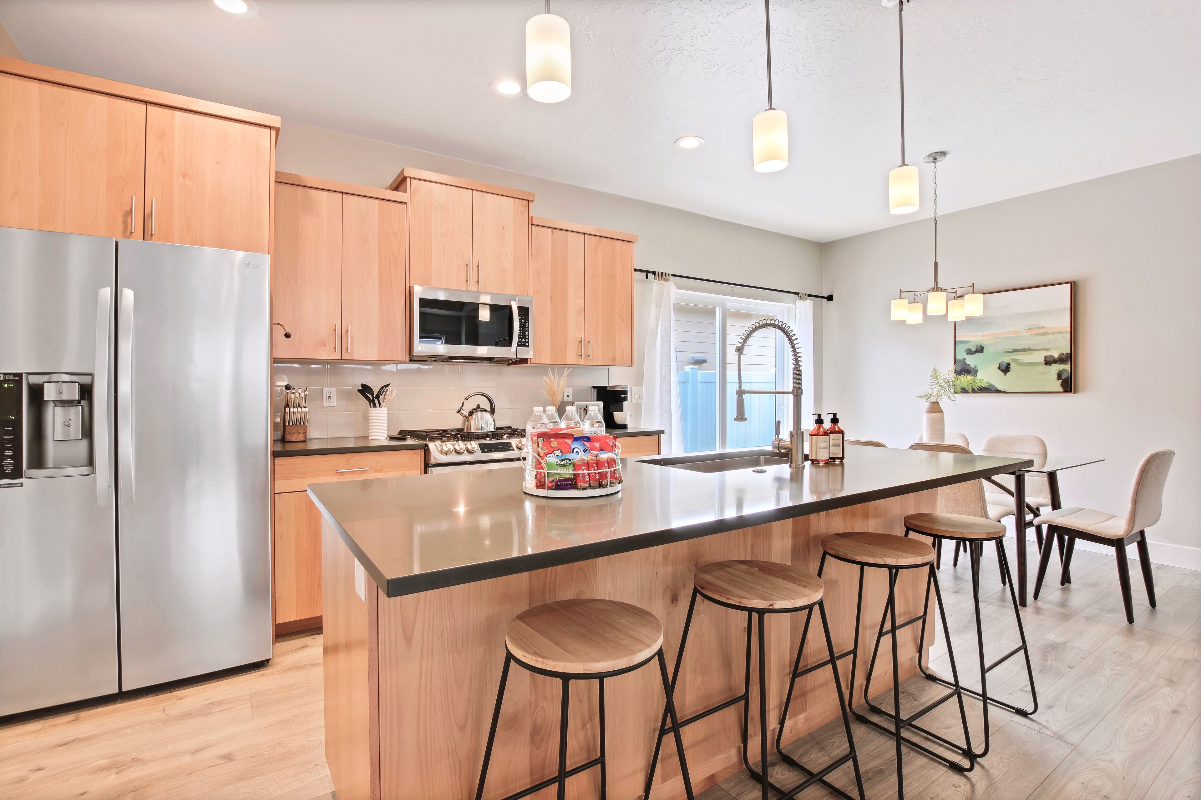 Una cocina moderna con electrodomésticos de acero inoxidable, armarios de madera y una isla central con taburetes de bar.