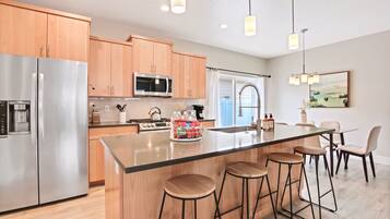 Una cocina moderna con electrodomésticos de acero inoxidable, armarios de madera y una isla central con taburetes de bar.