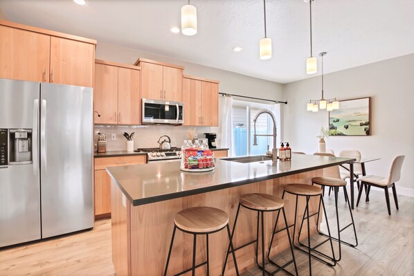A modern kitchen with stainless steel appliances, wooden cabinets, and a central island with bar stools.