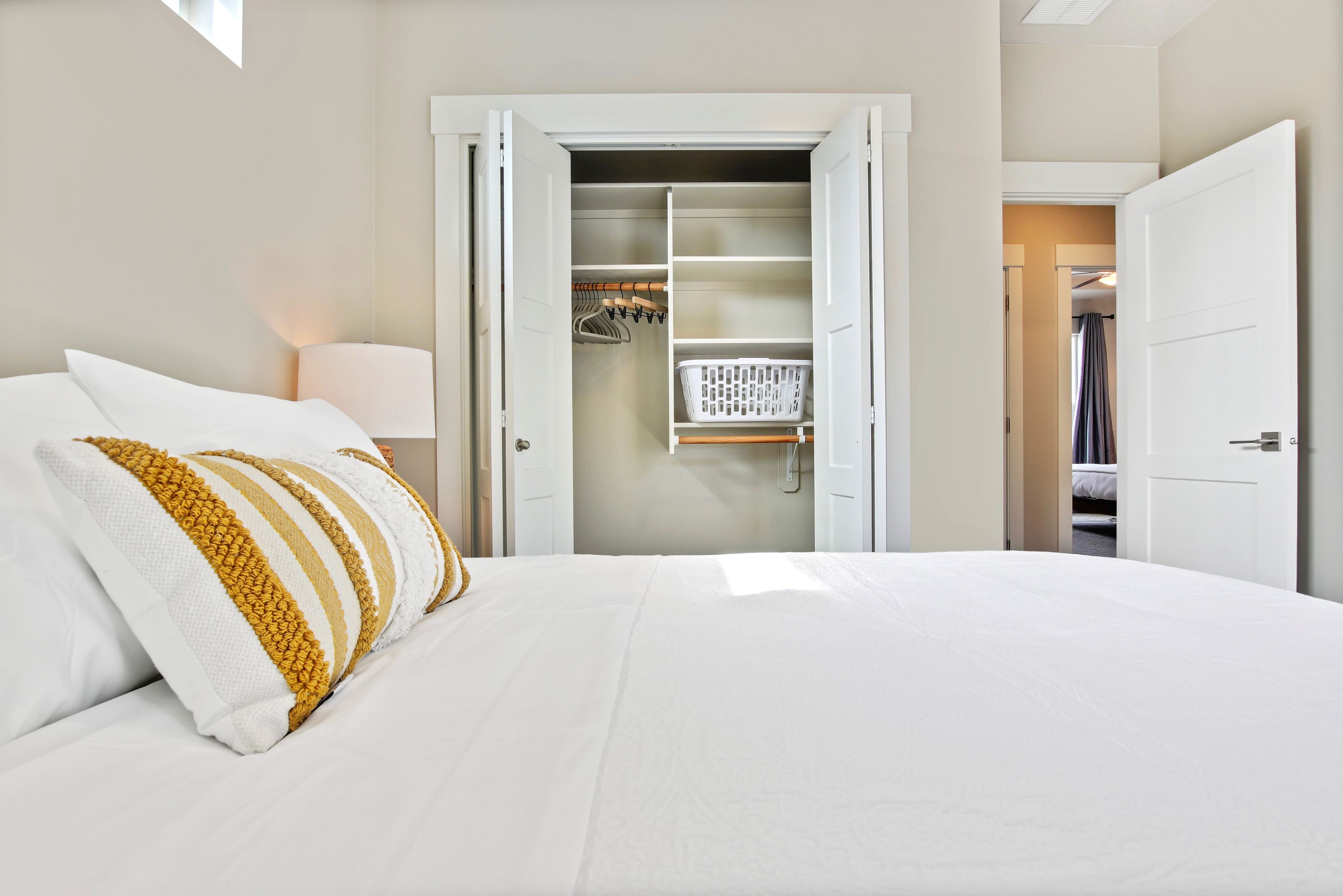 Una habitación de hotel con una cama, un armario y un vestidor con ropa colgada.