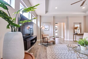 A modern living room with a fireplace, a large plant, a comfortable seating area, and a view of the hallway. - Top Rated Meridian Retreat • Clean & Spacious • Prime Central Location (Meridian)