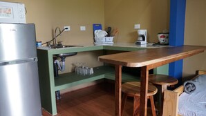 A compact kitchen with a built-in refrigerator, a coffee maker, and a sink.