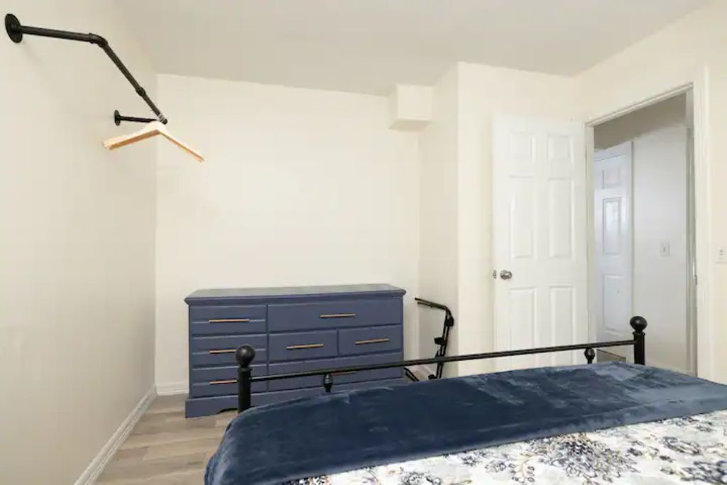 A bedroom with a bed, a dresser, and a door.