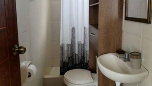 A bathroom with a toilet, sink, and a shower curtain with a cityscape design.