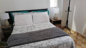 A neatly made bed with a floral bedspread, two bedside lamps, and a floor lamp.