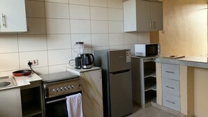 A kitchen with a stove, oven, refrigerator, microwave, and a kettle. - Entire two bedroom apartment in  Dar es salaam (Dar es Salaam(city))