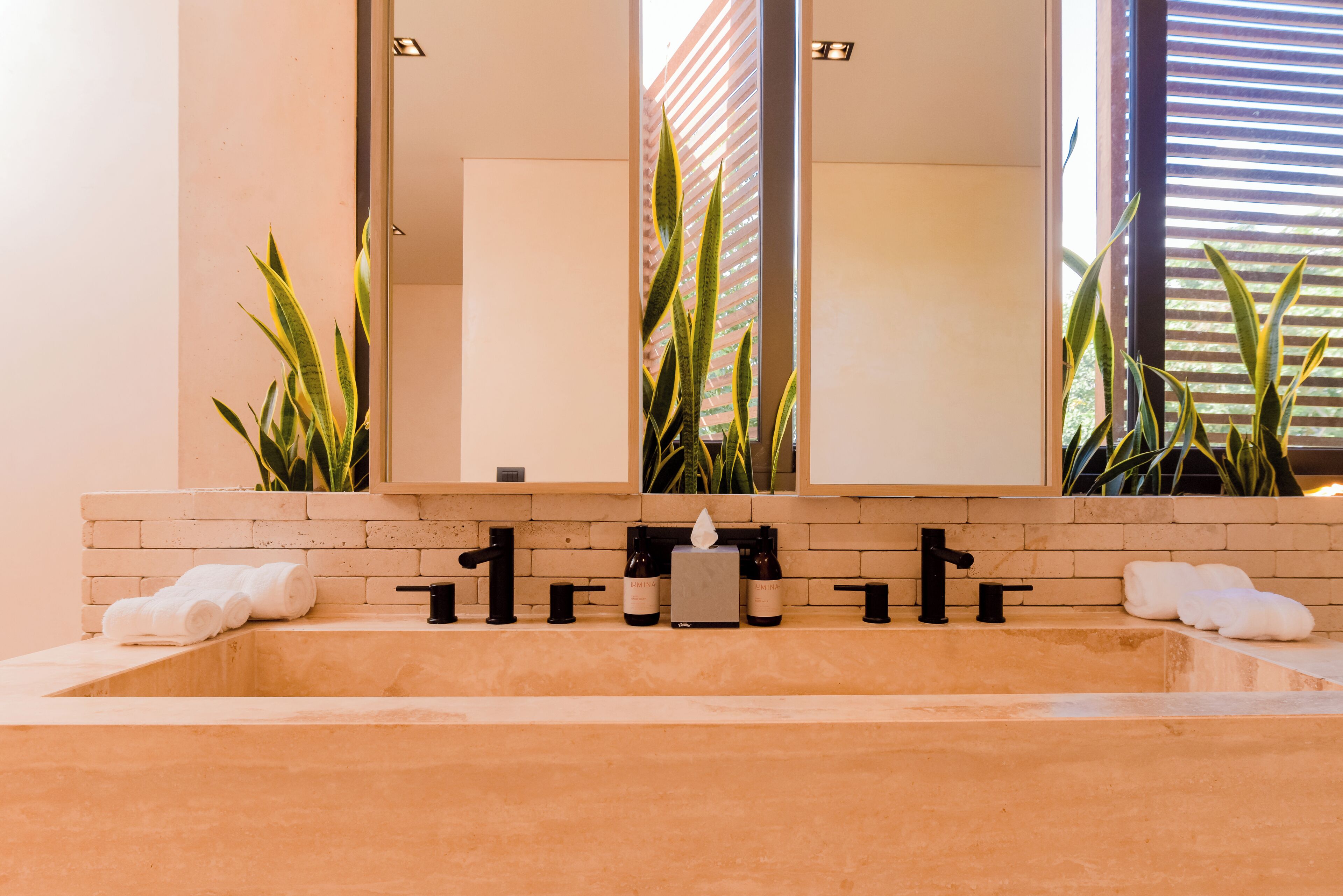 A modern bathroom with a large mirror, a bathtub, and a sink with black fixtures.