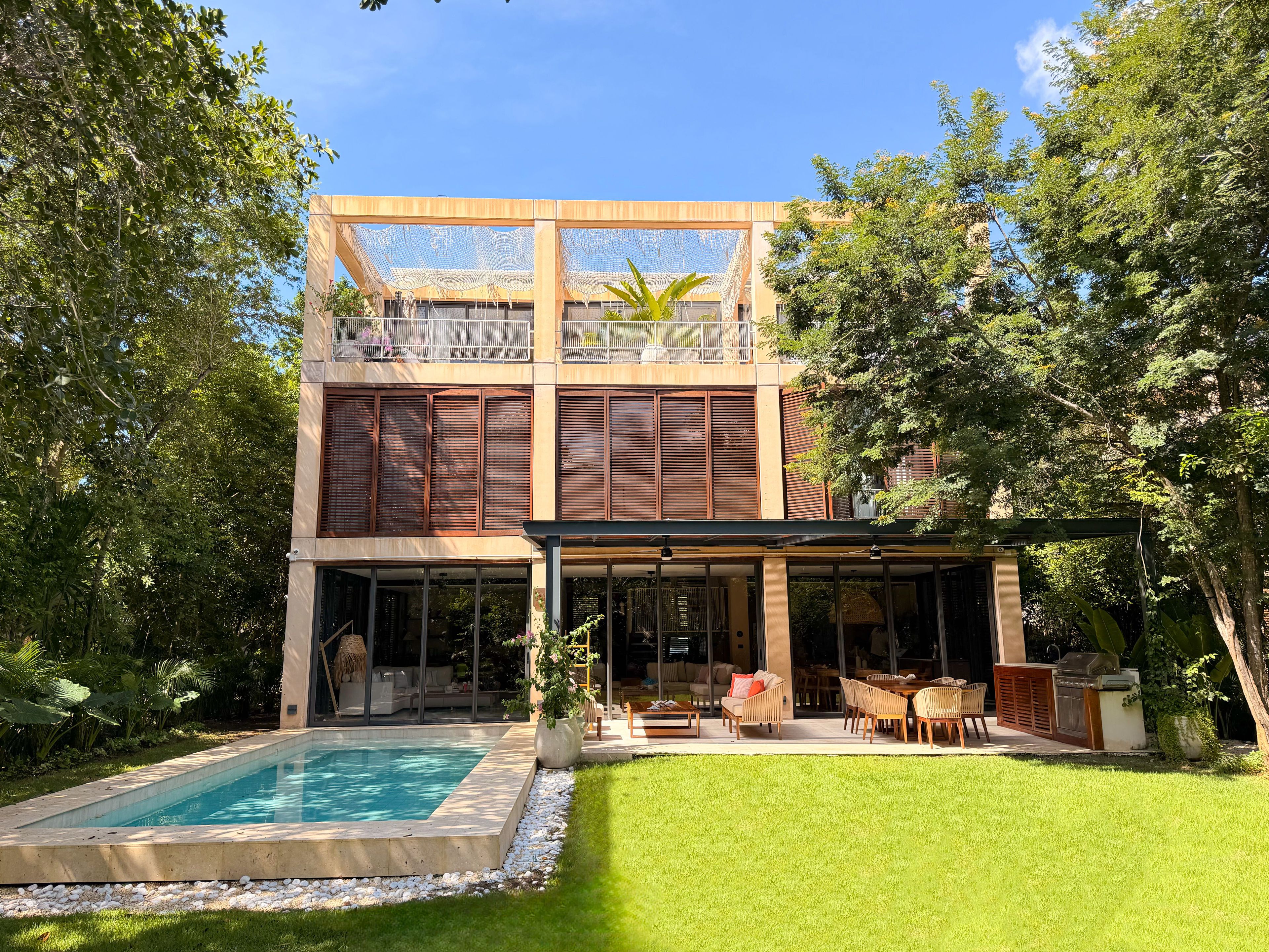 A modern two-story house with a swimming pool, outdoor seating, and a covered patio.