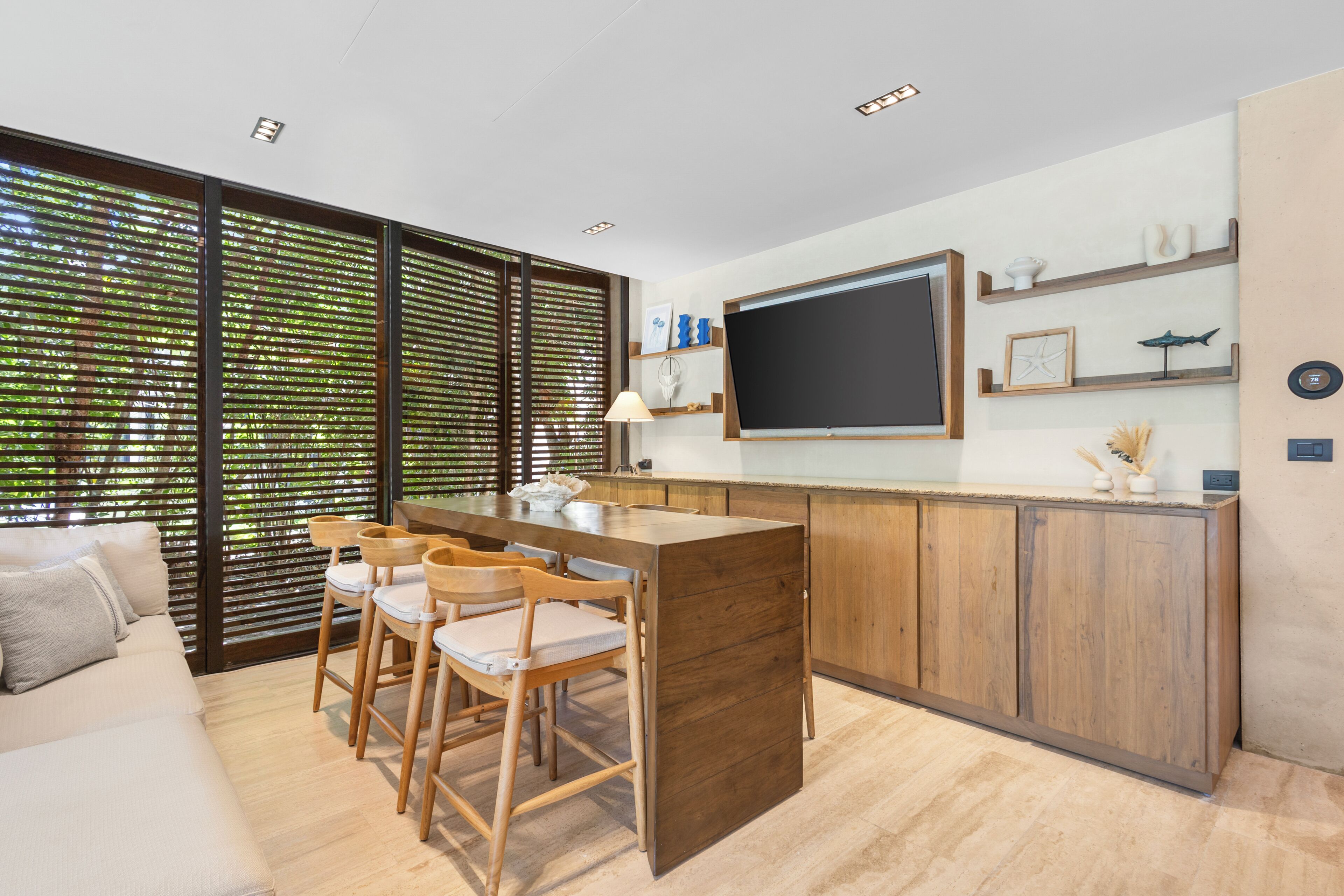 A modern kitchen with a central island, wooden chairs, and a dining table.