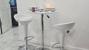 Ein modernes Badezimmer mit einem weißen Waschtisch, einem runden Tisch mit einer Kerze und einem Spiegel.