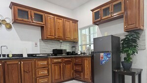 Eine Küche mit Holzausstattung, einem Kühlschrank, einer Spüle und einem Topfpflanzen.
